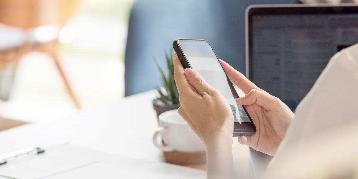 Female is on her mobile at work, looking at her Honeybee digital employee benefits plan